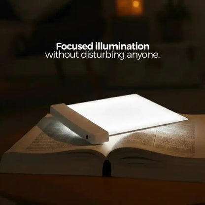 VisionGlow white flat panel on open book with focused bright illumination on wooden surface in dark room — reads without disturbing anyone